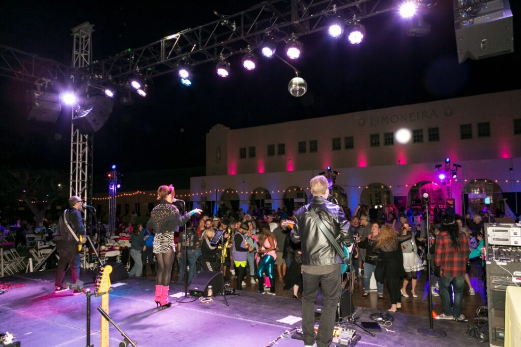 A crowd of people on stage with lights in the background.